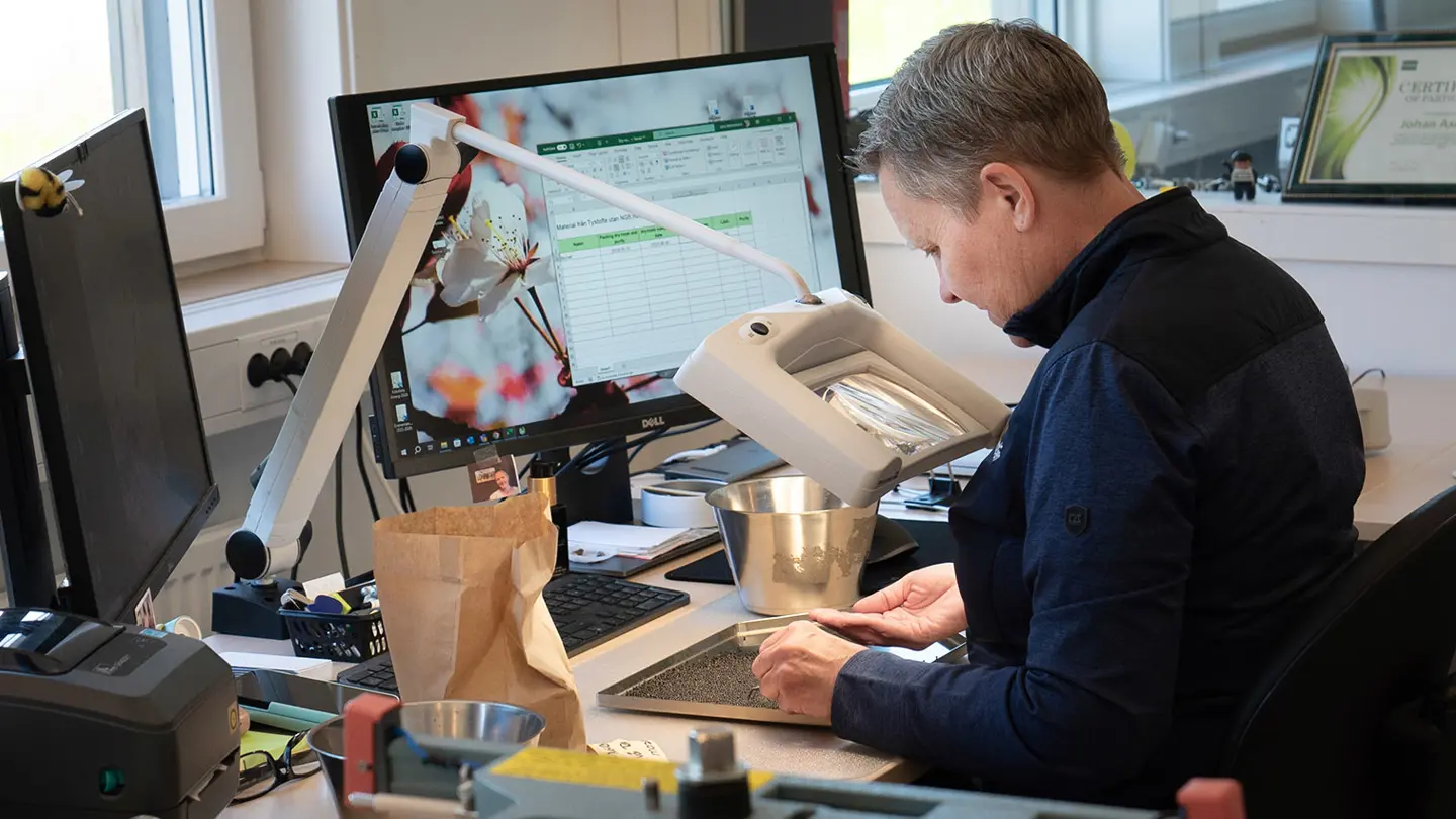 A person at a desk is studying something using a magnifier.